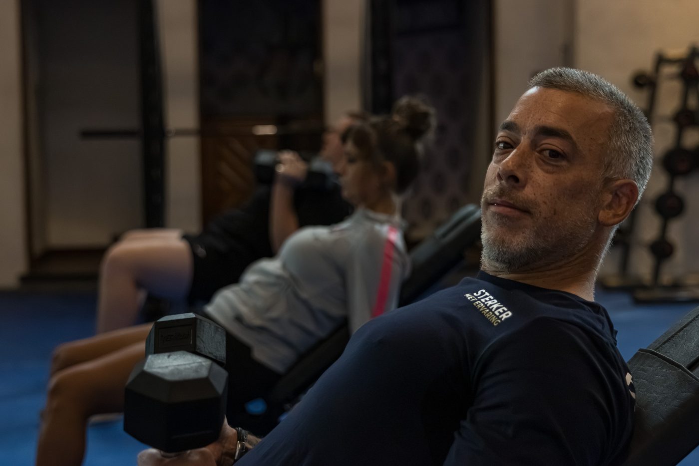 Trainer begeleidt een klant tijdens een oefening met gewichten