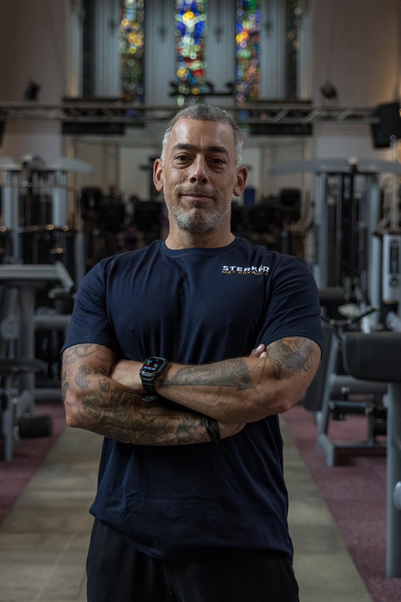 Personal trainer met de armen over elkaar in een tot sportschool verbouwde kerk